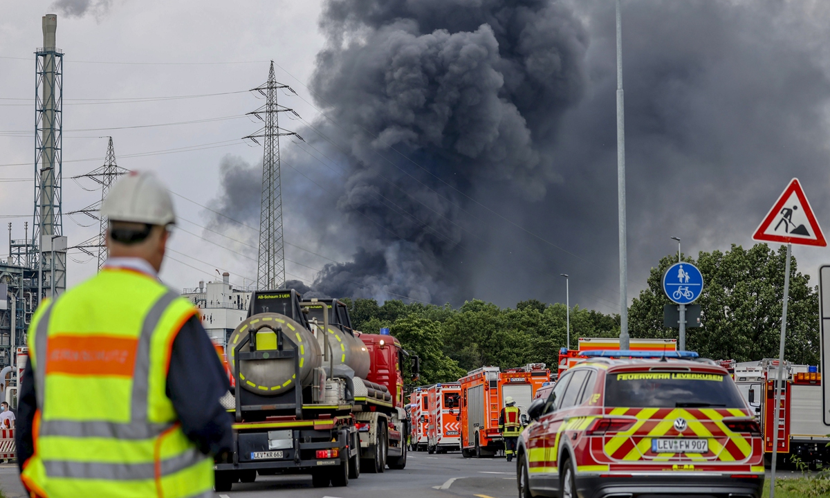 Emergency vehicles of the fire brigade, rescue services and police stand not far from an access road to the Chempark, over which a dark cloud of smoke is rising in Leverkusen, Germany, on Tuesday. Photo: VCG