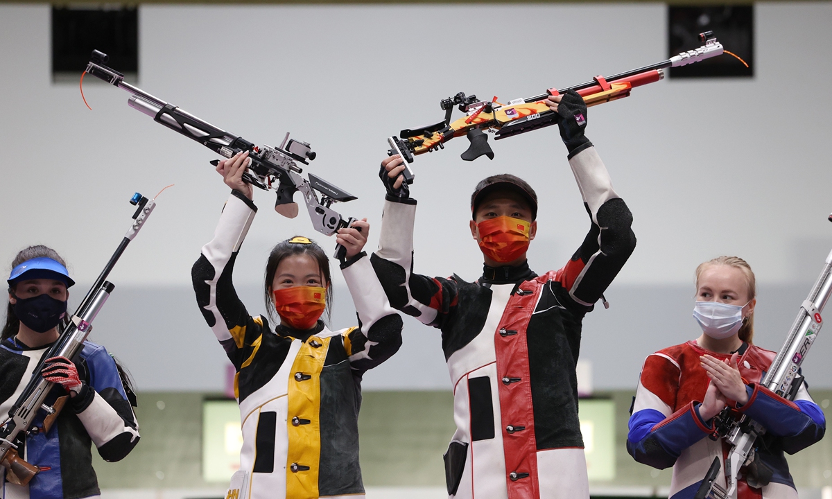 Gold medalists Yang Qian (center left) and Yang Haoran (center right) celebrate on the podium following the 10-meter air rifle mixed team finals on Tuesday in Tokyo. Photo: VCG