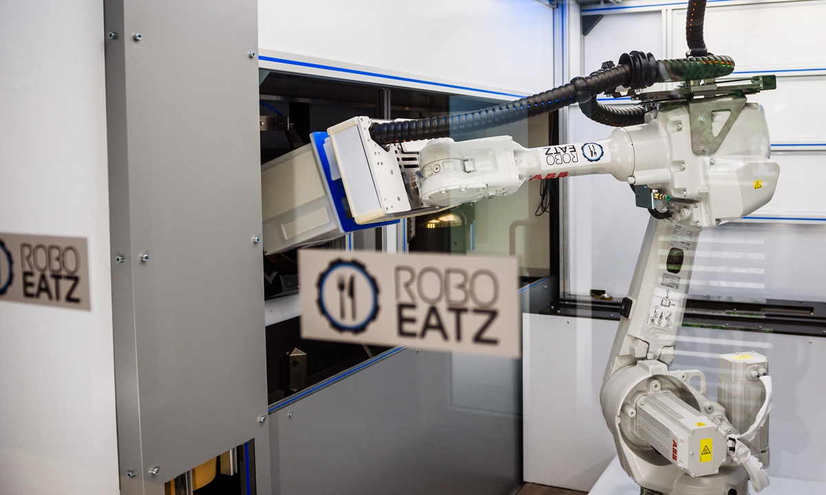 A pasta dish prepared with the help of a robot (pictured right) at the Roboeatz eatery in Riga. Photos: AFP