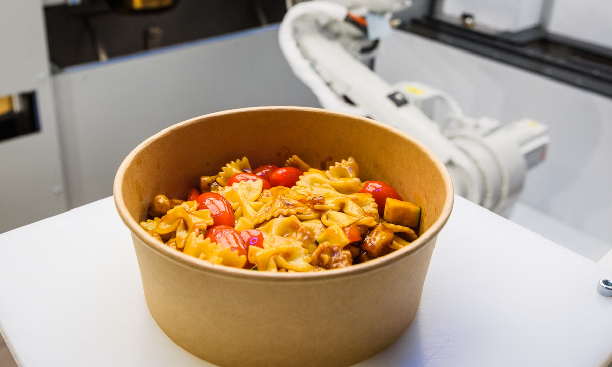 A pasta dish prepared with the help of a robot (pictured right) at the Roboeatz eatery in Riga. Photos: AFP