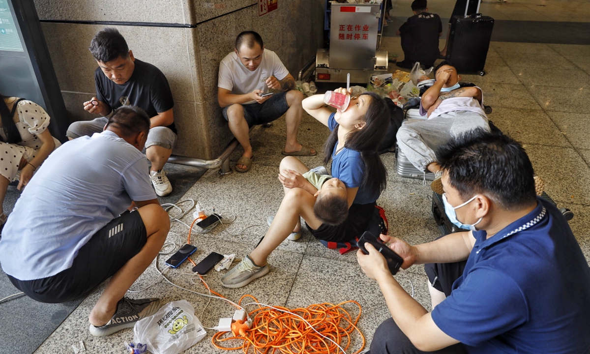 Passengers stuck at the Zhengzhou East Railway Station due to severe downpour sit in the waiting hall to recharge their phones. Photo: Li Hao/GT