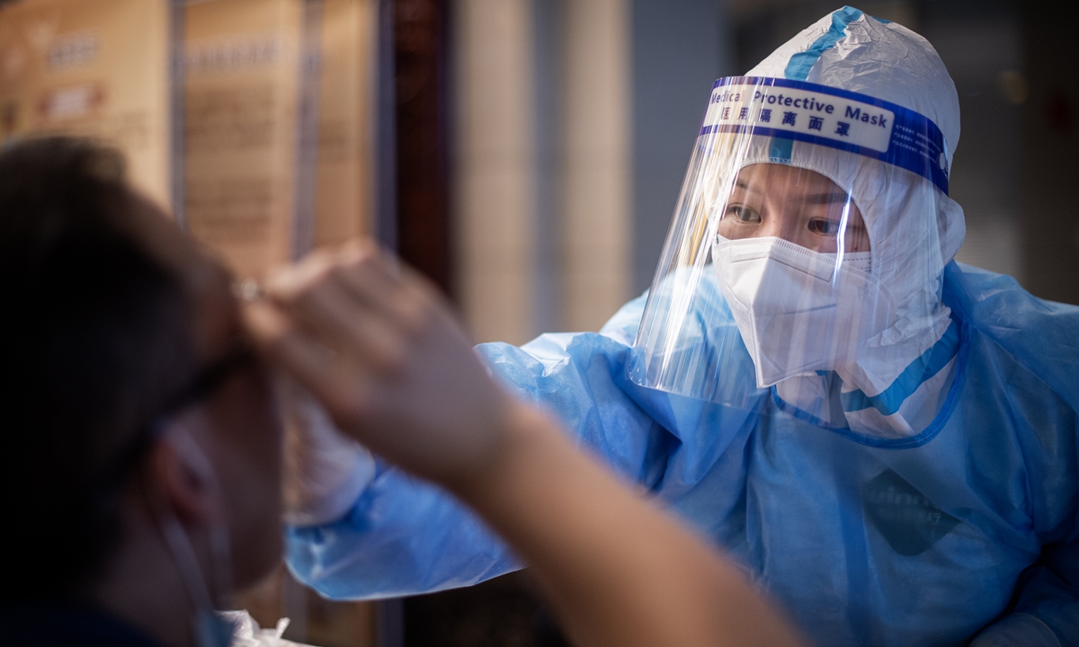 A medical staff takes the nucleic acid test for a local resident in Dongxihu District in Wuhan, central China's Hubei Province. Photo: The Paper