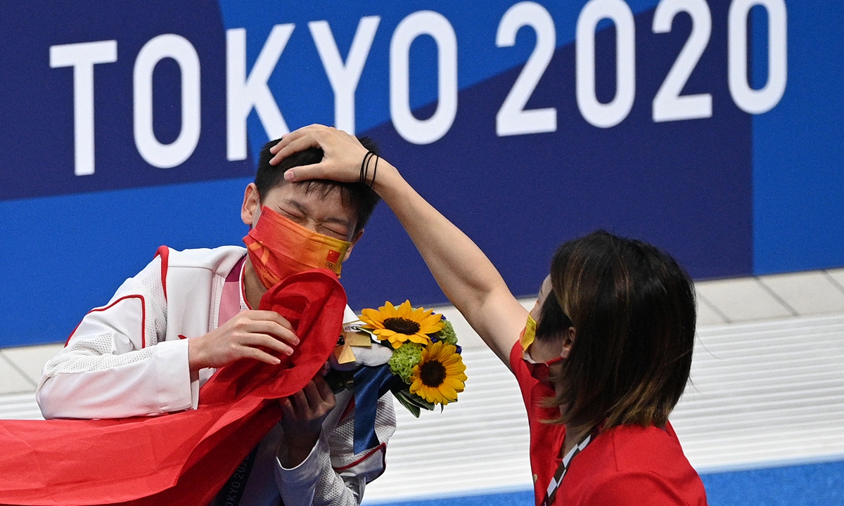 Gold medalist Quan Hongchan has her hair ruffled by a member of the coaching staff as she leaves the pool.  Photo: AFP