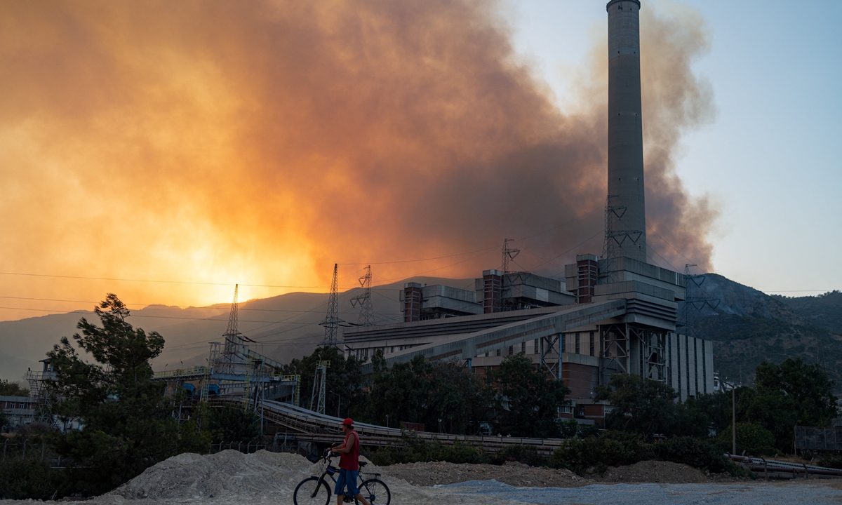 A man pushes a bicycle along a road in the vicinity of a forest fire close to the Kemerkoy Thermal Power Plant in northern Turkey on Wednesday. Photo: AFP