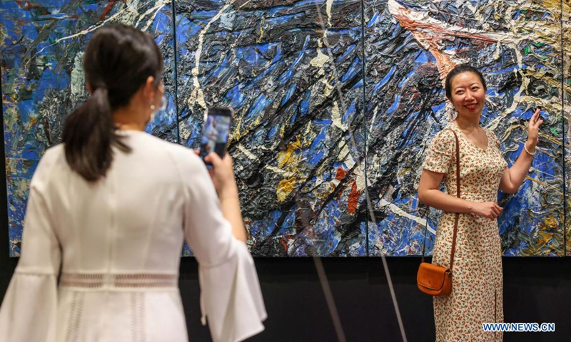 A visitor poses for a picture at an exhibition showcasing carpet art in east China's Shanghai Aug. 3, 2021. (Xinhua/Wang Xiang)