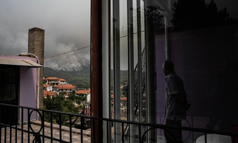 A man watches clouding smog from a wildfire at his house in the north of Evia island, Greece, on Aug. 5, 2021. Greek Prime Minister Kyriakos Mitsotakis said on Thursday evening that Greece is facing an extremely critical situation with multiple forest fires at the same time, while saving human lives is the government's top priority.Photo:Xinhua