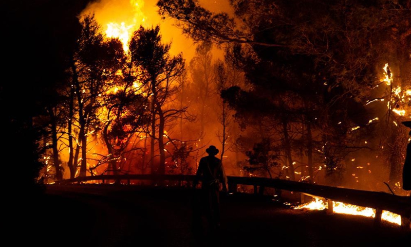 A volunteer tries to put out a wildfire in the north of Athens, Greece, on Aug. 5, 2021.Photo:Xinhua