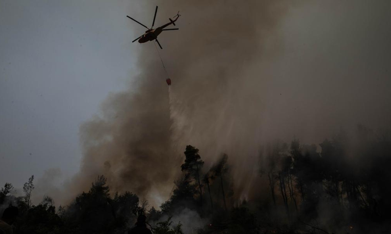 A helicopter tries to extinguish a wildfire in the north of Evia island, Greece, on Aug. 5, 2021. Greek Prime Minister Kyriakos Mitsotakis said on Thursday evening that Greece is facing an extremely critical situation with multiple forest fires at the same time, while saving human lives is the government's top priority.Photo:Xinhua