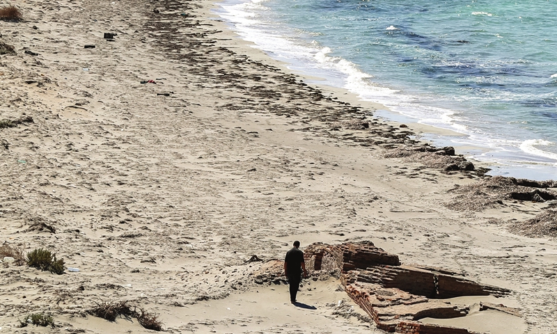 A man walks along the beach of Libya's Farwa Island, about 170 kilometers west of the capital and close to the border with Tunisia, on June 10. Photo: AFP