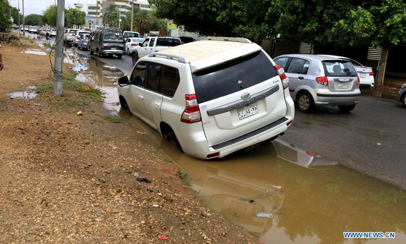 A car is seen trapped on a muddy side of the road after heavy rain hit Khartoum, Sudan, Aug. 8, 2021. (Photo by Mohamed Khidir/Xinhua)