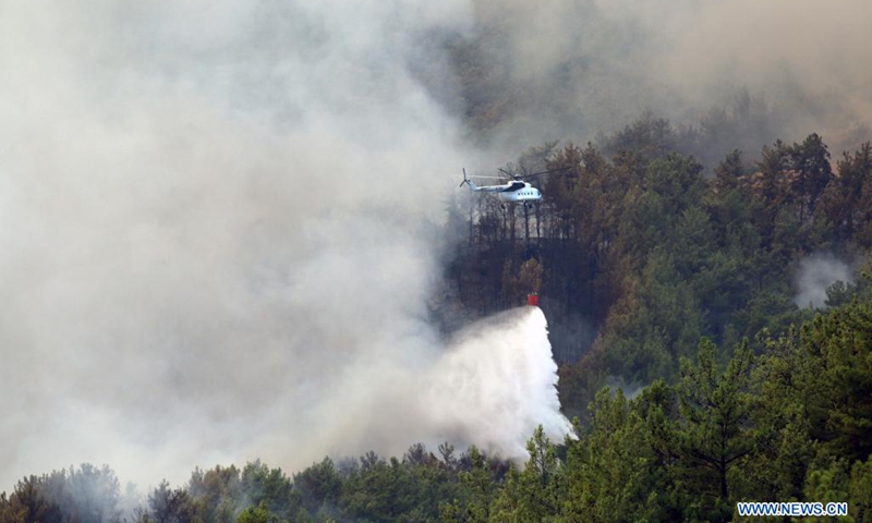 A helicopter douses wildfires in Koycegiz, Mugla province, southwestern Turkey, on Aug. 8, 2021. Turkey has been battling massive wildfires that erupted in southern and southwestern coastal resort towns 12 days ago. Most of them have been taken under control, according to municipal authorities.(Photo: Xinhua)
