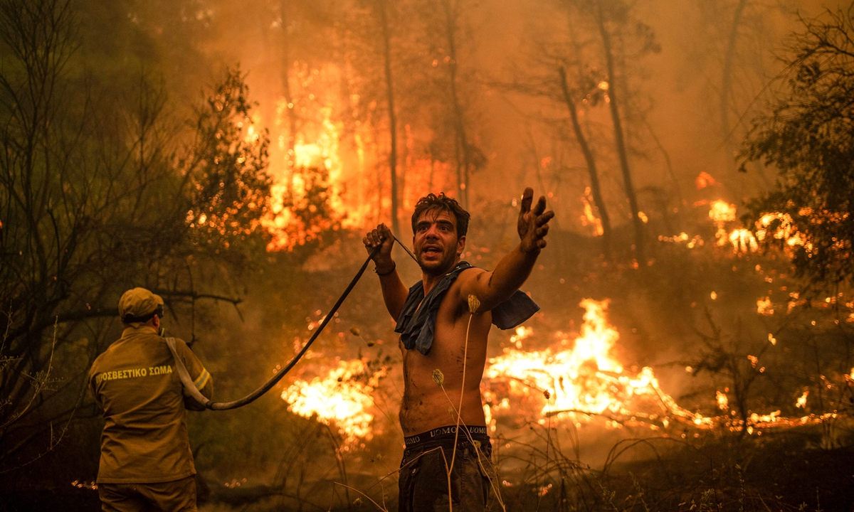 A local resident gestures as he holds an empty water hose during an attempt to extinguish forest fires approaching the village of Pefki on Evia island, Greece's second largest island on Sunday. Hundreds of Greek firefighters fought desperately to control wildfires on the island that have charred vast areas of pine forest, destroyed homes and forced tourists and locals to flee. Photo: AFP