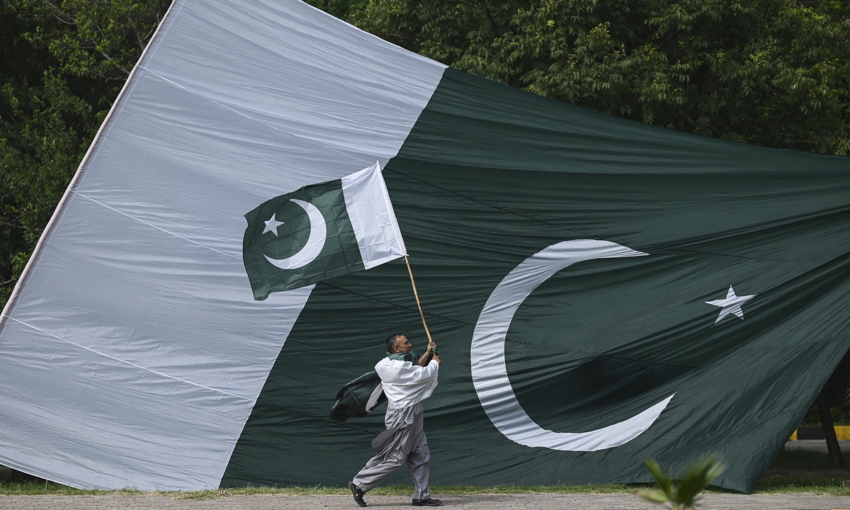 A man holds a national flag of Pakistan as he walks along a street in Islamabad on Tuesday, ahead of the country's 75th Independence Day, which marks the end of British colonial rule. A number of award ceremonies are often held on this day, and Pakistanis hoist the national flag atop their homes or display it prominently on their vehicles and attire. Photo: AFP
