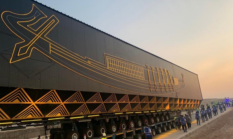 Staff members escort the first Khufu solar boat, carried by a specialized large vehicle, to the Grand Egyptian Museum at the Giza Pyramids scenic spot in Giza, Egypt, Aug. 6, 2021.(Photo: Xinhua)