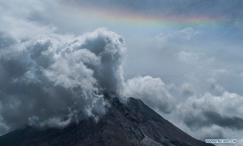 Photo taken on Aug. 9, 2021 shows a rainbow above the skyline while Mount Sinabung spewing volcanic materials and smoke as seen from Gamber village in Karo, North Sumatra, Indonesia.(Photo: Xinhua)