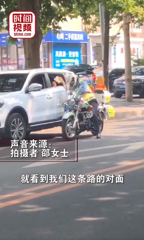 A traffic policeman riding a motorcycle stopped by the illegally parked car, but instead of giving it a ticket, he used the tickets as a fan to cool down the kid through the window, who was left alone in the car. Photo: screenshot of Btime.com on Sina Weibo. 