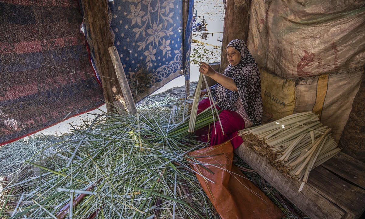 A woman uses a thread to slice papyrus into thin strips at the workshop in the village of Al-Qaramus in Sharqiyah province, Egypt on July 28. Photo: AFP