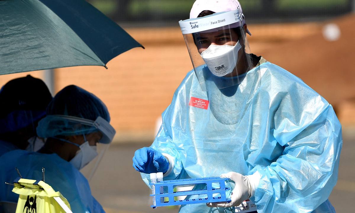 A health worker collects swab samples at a COVID-19  drive through testing site in the Smithfield suburb of Sydney on Thursday. Australia is battling to get on top of the fast-moving Delta strain that has plunged Sydney and Melbourne into hard lockdowns.Photo: AFP