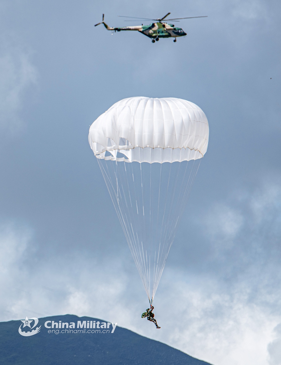 A paratrooper assigned to a special operations brigade under the PLA Tibet Military Command opens his parachute while descending to the drop zone after jumping out of a transport helicopter during a training exercise on July 30, 2021. This exercise effectively beefed up the paratroopers’ multi-dimensional assault and penetrating strike capabilities on plateau. (eng.chinamil.com.cn/Photo by Wang Shudong)