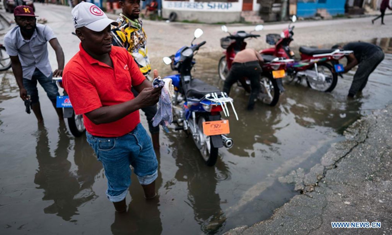 A man cleans a shoe in a puddle after an earthquake, in Les Cayes, Haiti, on Aug. 17, 2021. The death toll from a powerful earthquake that struck southwest Haiti on Saturday climbed to 1,941, the Caribbean island's Civil Protection Agency reported on Tuesday. (Xinhua/David de la Paz)