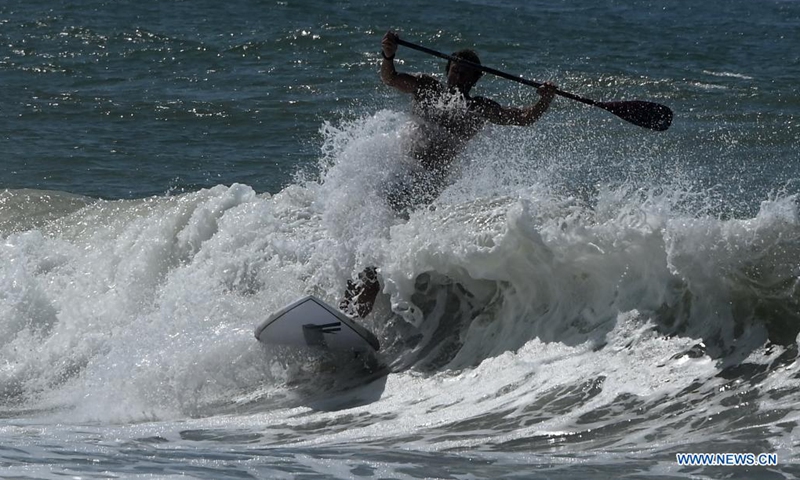 A man surfs the waves off Ladispoli in Lazio, Italy, on Aug. 17, 2021. (Photo by Alberto Lingria/Xinhua)