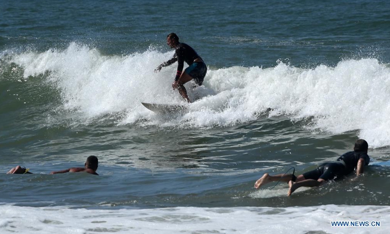 People surf the waves off Ladispoli in Lazio, Italy, on Aug. 17, 2021. (Photo by Alberto Lingria/Xinhua)