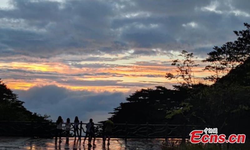 As the sky is illuminated by the sunset glow, mist and sea of clouds shroud Mount Huangshan after rain in east China's Anhui Province, Aug. 15, 2021, forming a glittering scenery. (Photo: China News Service/Xie Fei)

