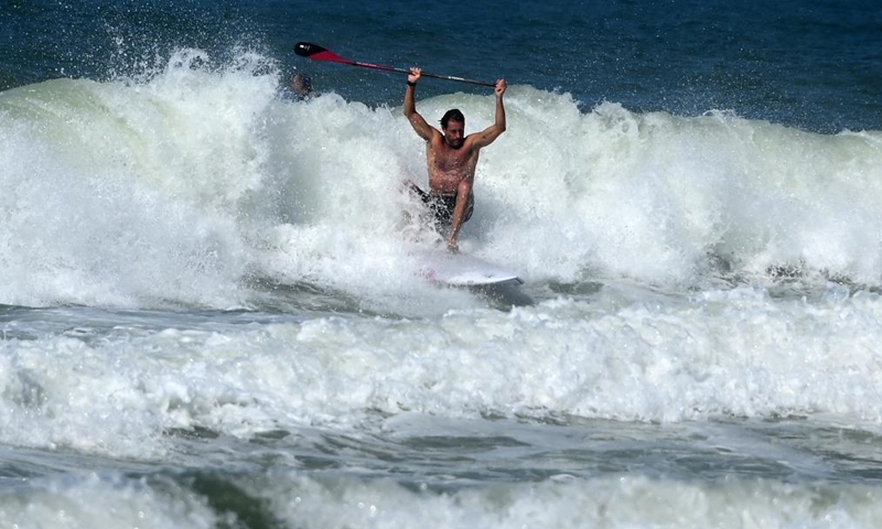 A man surfs the waves off Ladispoli in Lazio, Italy, on Aug. 17, 2021. (Photo by Alberto Lingria/Xinhua)