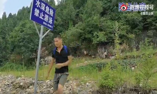 A policeman plays the role of a student carrying a backpack who goes to swim in a river, ignoring the warning sign 