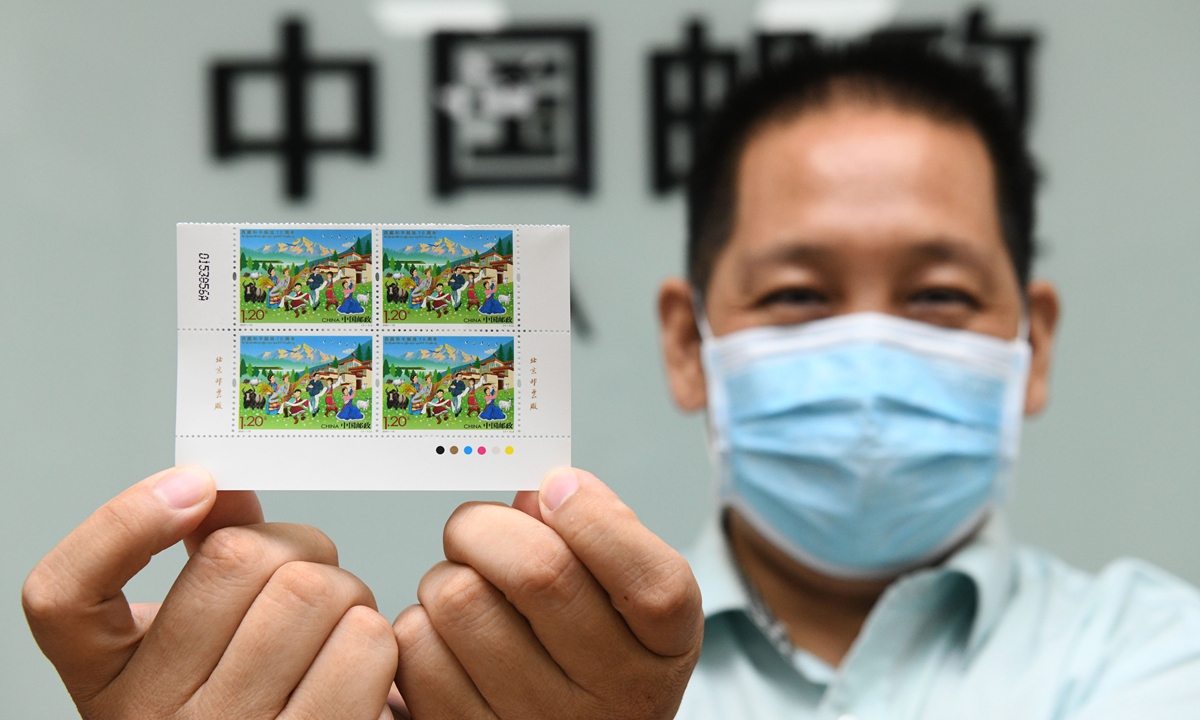 A China Post employee in North China's Hebei Province on Wednesday shows the commemorative stamps marking the 70th anniversary of the peaceful liberation of Tibet. Photo: IC