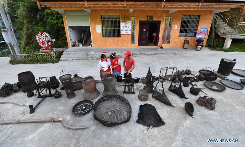 Students arrange collected old farm tools and life appliances at Wuying Village, which lies on the border between south China's Guangxi Zhuang Autonomous Region and southwest China's Guizhou Province, on Aug. 21, 2021. In the summer of 2021, a volunteer team consisted of college and middle school students led local pupils to participate in diverse activities, such as maintaining saplings, learning about intangible cultural heritages and collecting old farm tools for museums. (Xinhua/Huang Xiaobang)