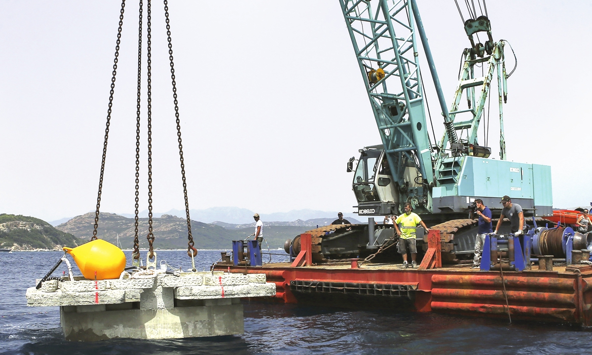 Workers anchor a yacht in the Sant' Amanza bay in the south of the French Mediterranean island of Corsica on August 11, 2021. Photo: AFP
