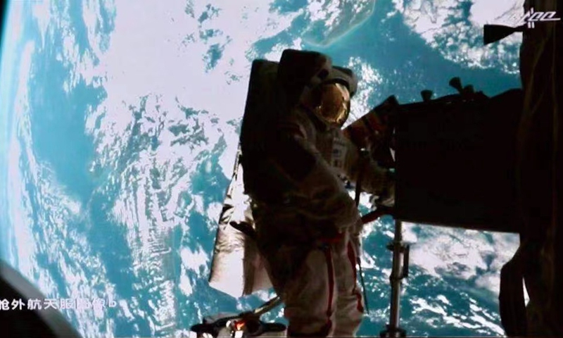 Nie standing on robotic arm takes photo with Earth. Photo: CMSA