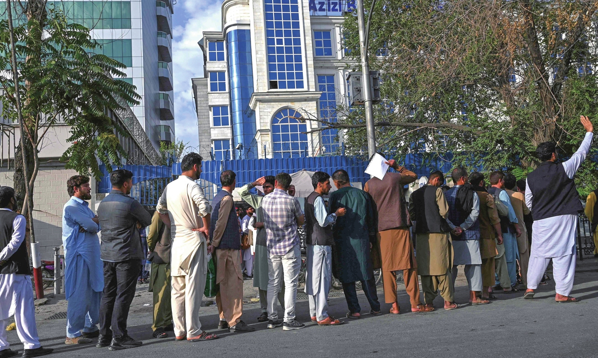 Afghan people stand in a queue as they wait for their turn to collect money from an ATM in front of a bank along a roadside in Kabul on Saturday, days after the Taliban's astonishing takeover of Afghanistan. Photo: VCG