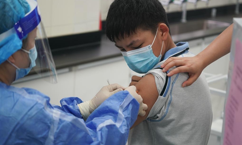 A student receives a dose of COVID-19 vaccine at a vaccination point of Wenshu middle school in Nanjing, east China's Jiangsu Province, Aug. 23, 2021. Nanjing started administering the first dose of COVID-19 vaccines among minors aged between 12 and 17. (Xinhua/Ji Chunpeng) 