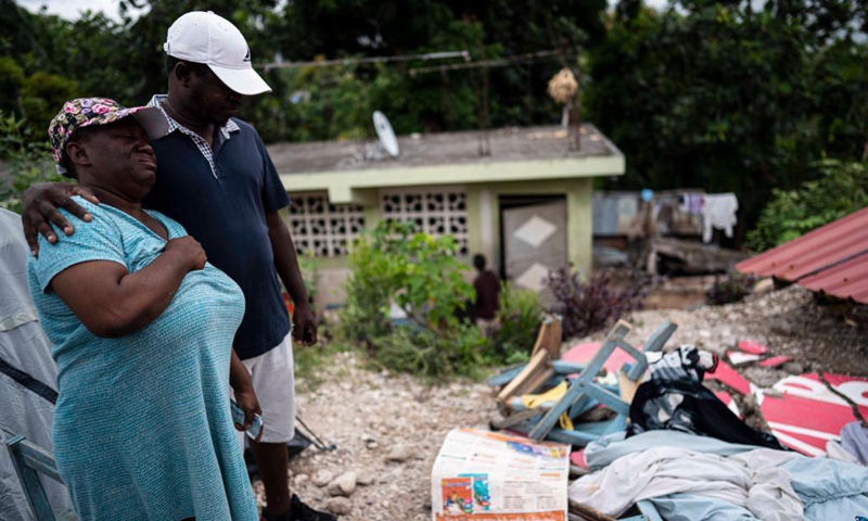 Photo taken on Aug. 21, 2021 shows people standing in front of a damaged house in Marceline, near Les Cayes, Haiti. (Photo: Xinhua)