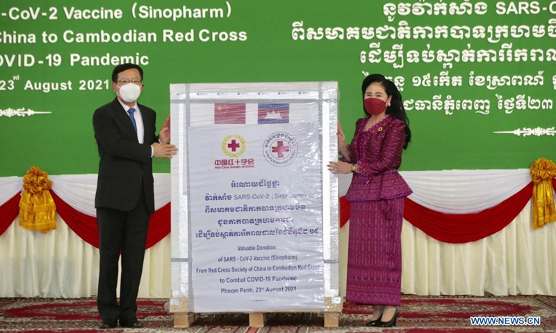 Chinese Ambassador to Cambodia Wang Wentian (L) hands over the China-donated Sinopharm COVID-19 vaccine to Cambodian Red Cross President Bun Rany, at the Phnom Penh International Airport in Phnom Penh, Cambodia on Aug. 23, 2021. China on Monday donated additional 600,000 doses of the Sinopharm COVID-19 vaccine to Cambodia, giving the Southeast Asian country another boost to its immunization program. (Photo by Phearum/Xinhua)