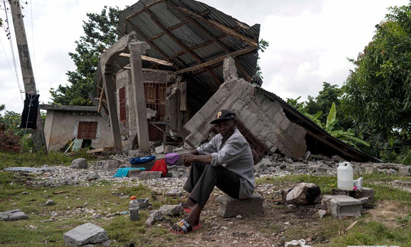 Photo taken on Aug. 21, 2021 shows a man resting in front of a damaged house in Marceline, near Les Cayes, Haiti. (Photo: Xinhua)