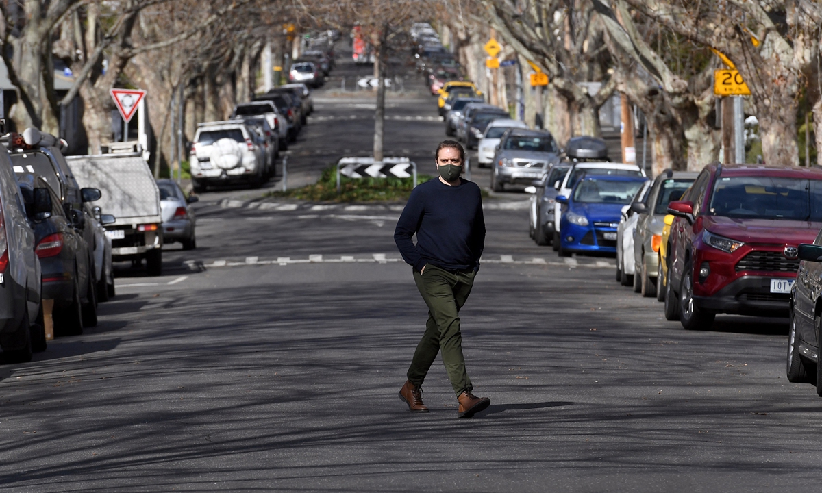A man crosses an empty street in Melbourne, Australia on Monday, as the city experiences its sixth lockdown while battling an outbreak of the Delta variant of coronavirus. Photo: AFP
