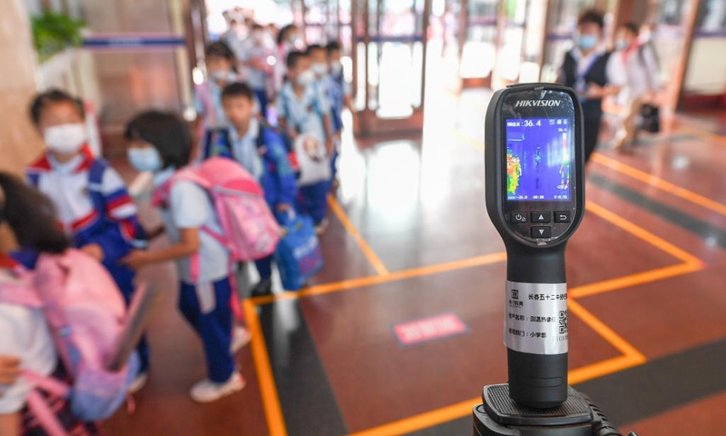 Primary students receive temperature check at a school in Changchun, capital of northeast China's Jilin Province, Aug. 23, 2021. Primary and middle schools in Changchun greeted their new semesters on Monday. (Xinhua/Zhang Nan)

