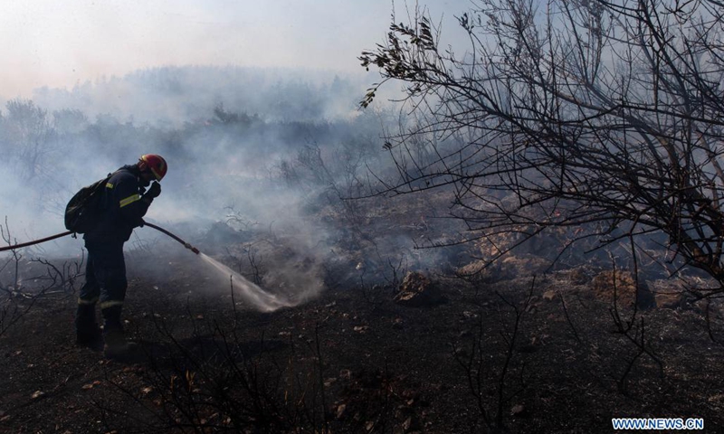 A firefighter battles a wildfire in a burned forest in Vilia to the northwest of Athens, Greece, on Aug. 23, 2021. A new wildfire broke out here on Monday, burning in thick forest land.(Photo: Xinhua)
