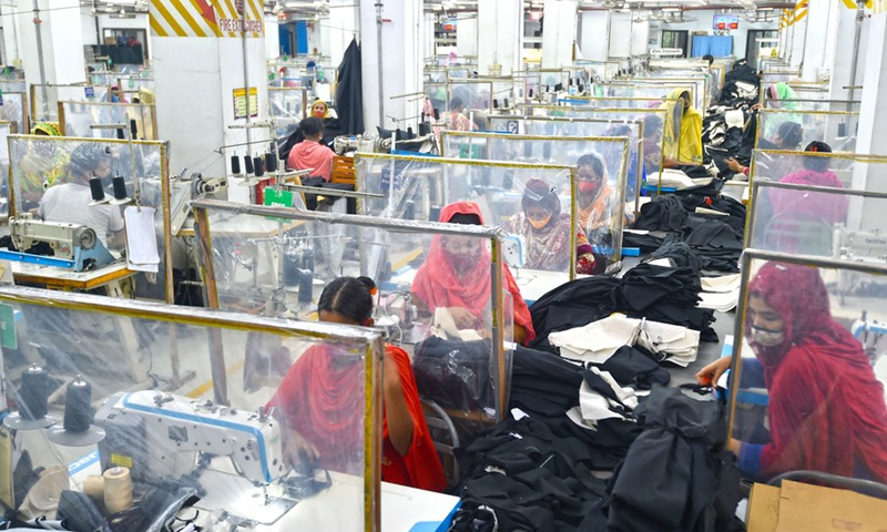 Photo taken on Aug. 23, 2021, shows sewing desks with plastic curtains installed to maintain social distancing for workers at a garment factory in Dhaka, Bangladesh.(Photo: Xinhua)