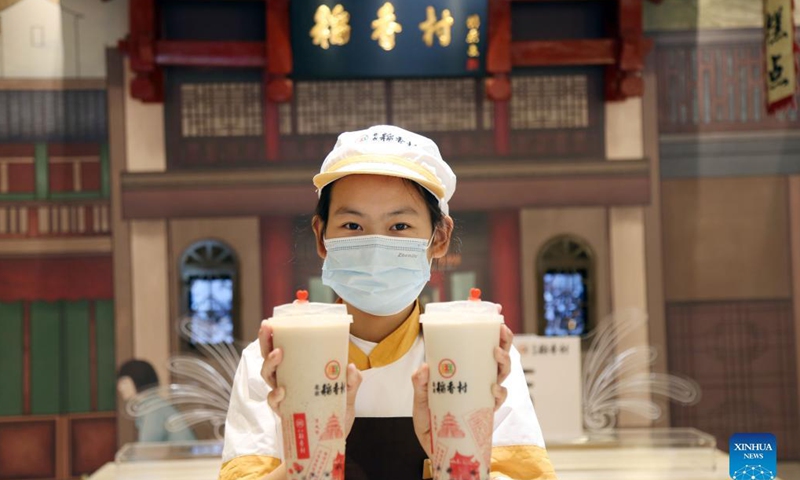 A staff member of Daoxiangcun holds two cups of the Beijing-style tea drinks in Beijing, capital of China, Aug. 25, 2021.Photo: Xinhua
