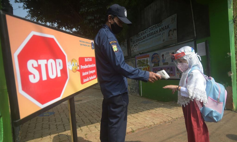 A security guard takes the temperature of a student at a school reopened after several months due to COVID-19 pandemic in Jakarta, Indonesia, Aug. 30, 2021. Photo:Xinhua
