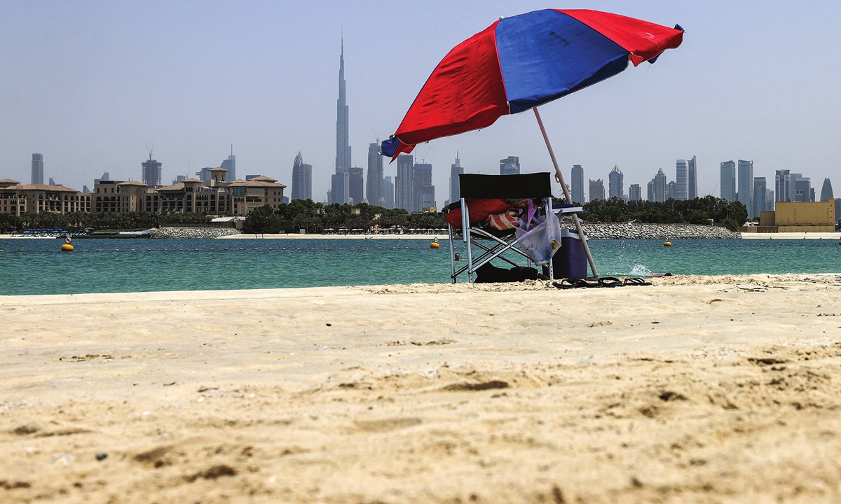 An umbrella covers a chair at an almost empty beach in Dubai, UAE on August 25, 2021 amid a heatwave. Photo: AFP