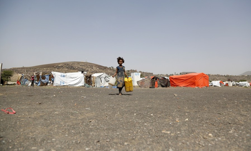A displaced girl carries a plastic bucket to fill it with water in Dharawan displaced camp in north Sanaa, Yemen, Aug. 30, 2021. (Photo: Xinhua)