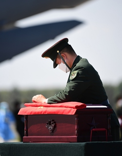 An honor guard soldier carefully checks the casket containing the remains of a Chinese People's Volunteers soldier. Photo: Xinhua