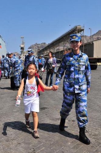 A female soldier of the frigate Linyi helping a child evacuee board the warship on March 29, 2015.