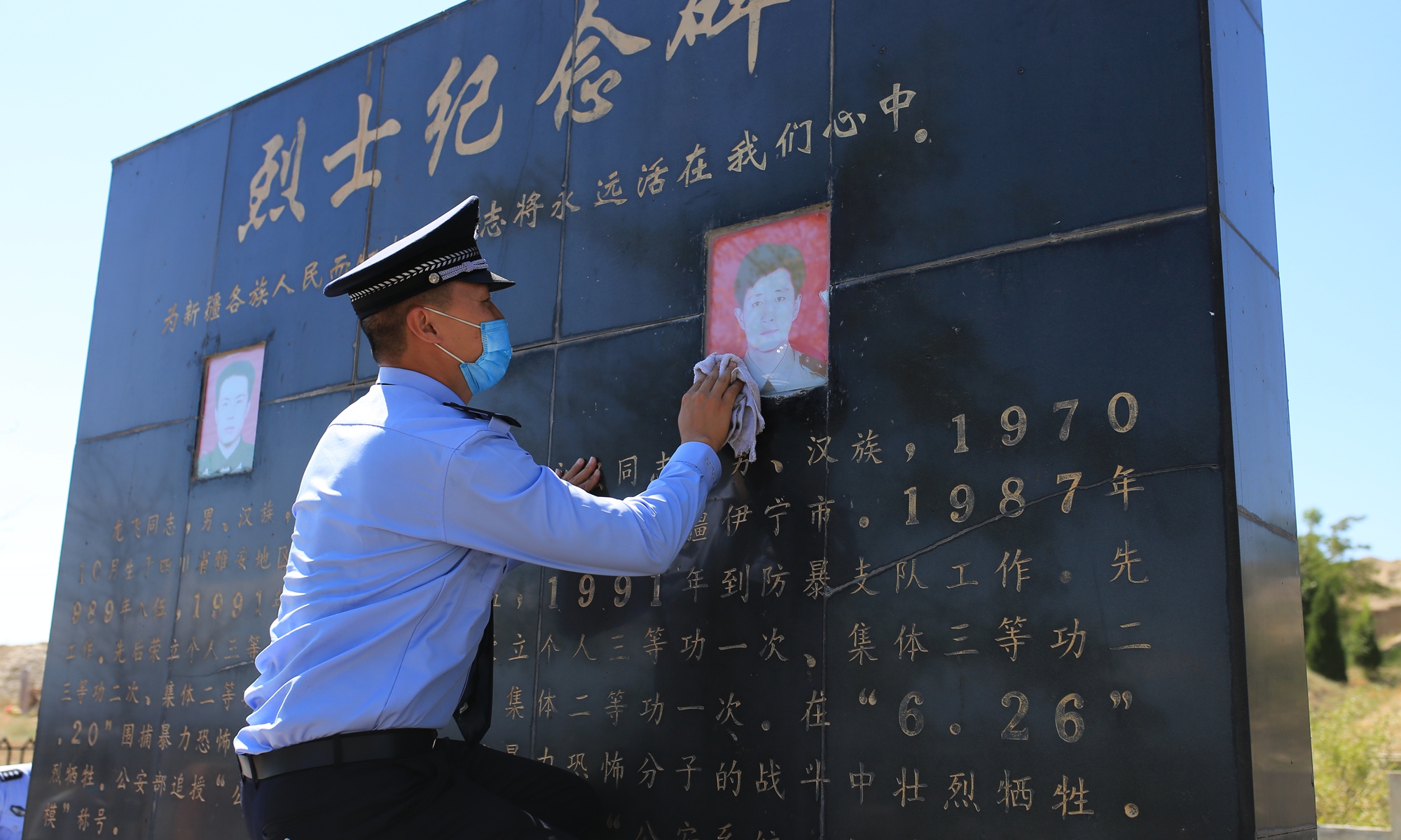 A police officer wipes the memorial stone for Long Fei and Kong Yongqiang.
