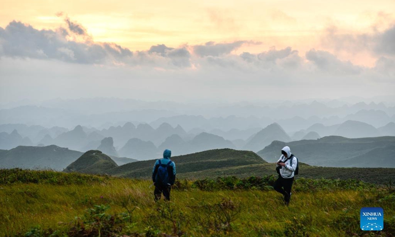 Tourists view the sunrise at a scenic spot in Hezhang County, southwest China's Guizhou Province, Sept. 4, 2021. Hezhang County, featuring beautiful natural scenery and distinctive culture, has ramped up efforts in improving tourism facilities and boosting tourism industry in recent years. Tourism development of the county has given impetus to its rural revitalization. Statistics show that the county has received 4.34 million visitor trips from January to August this year. (Xinhua/Yang Wenbin) 